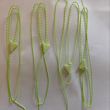 Several neon green 1mm braided guyline cords laid out on a white surface, each with a small glow in the dark line lock attached to the end