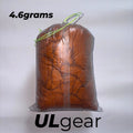White DCF Dyneema stuff sack with orange stitching and glow in the dark cord lock