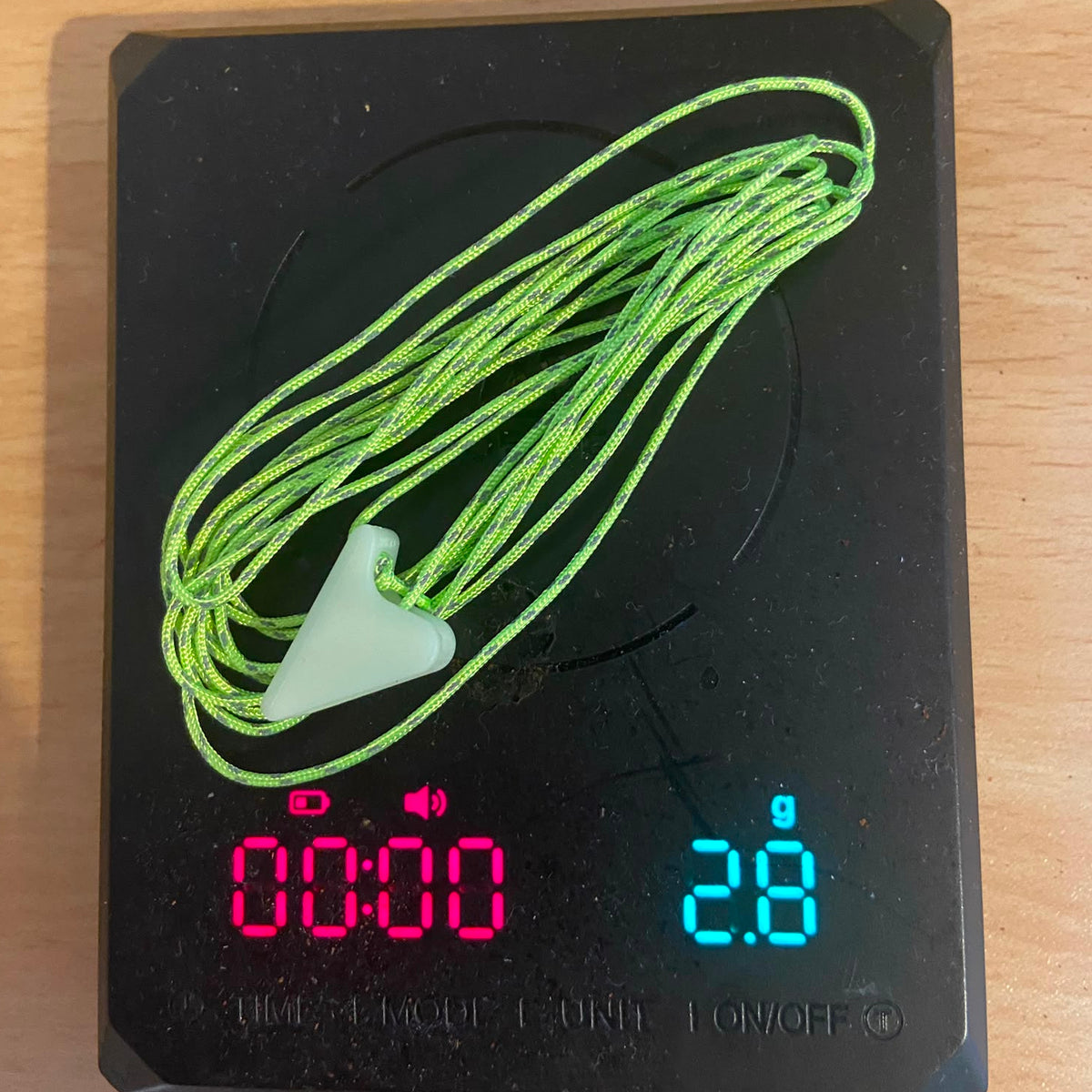 light weight guyline kit sitting on a scale showing the low weight of 2.8 grams for the product